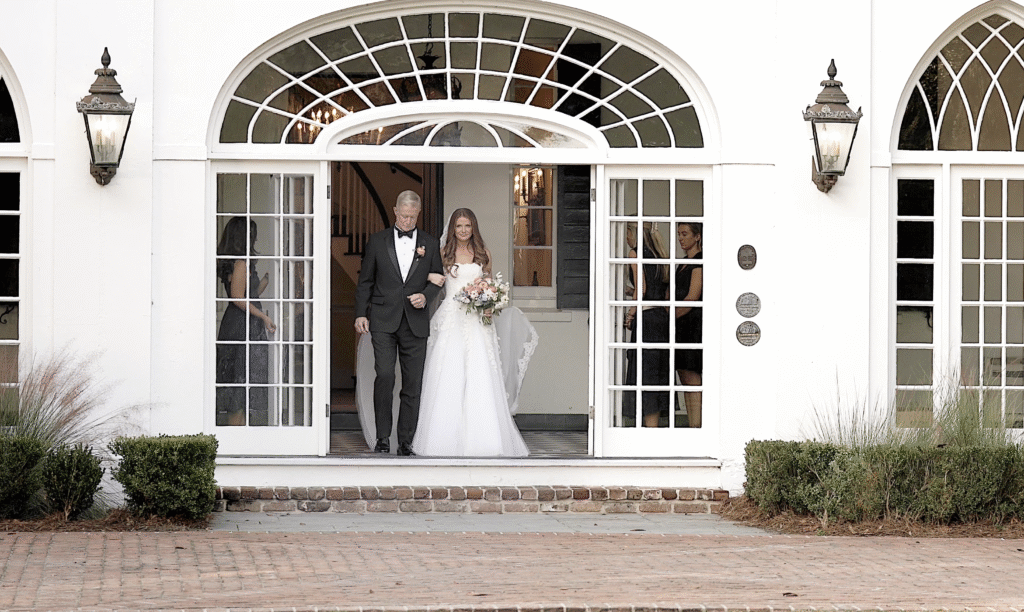 Bride and her father walk out of the door of the house at Lowndes Grove.